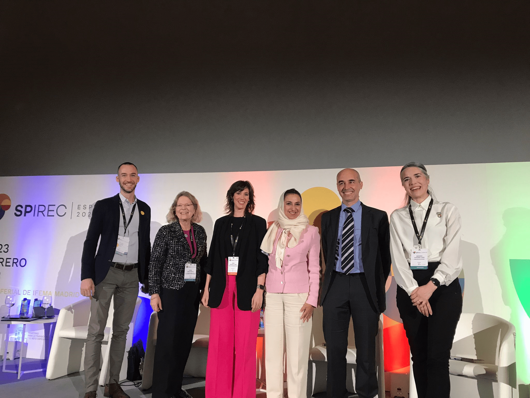 SPIREC2023 Panellists standing on stage with conference poster as a backdrop